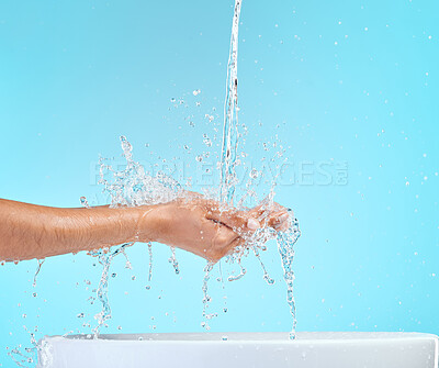 Buy stock photo Cropped shot of an unrecognisable woman cupping her hands to catch water against a blue background in the studio