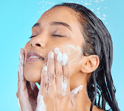 Buy stock photo Shower foam, face and black woman cleaning with water liquid for hydration, beauty healthcare soap or skincare hygiene. Self care studio, spa salon and relax model washing isolated on blue background