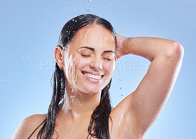 Buy stock photo Shot of a beautiful young woman enjoying a refreshing shower against a blue background