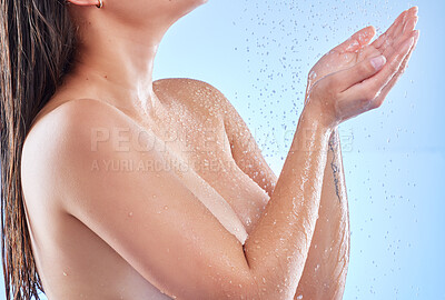 Buy stock photo Shot of a beautiful young woman enjoying a refreshing shower against a blue background