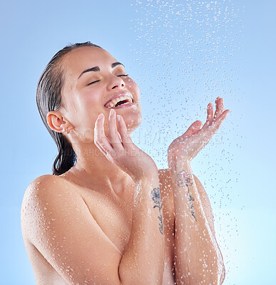 Buy stock photo Shot of a beautiful young woman enjoying a refreshing shower against a blue background