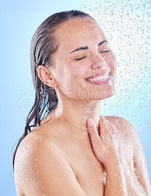 Buy stock photo Shot of a beautiful young woman enjoying a refreshing shower against a blue background