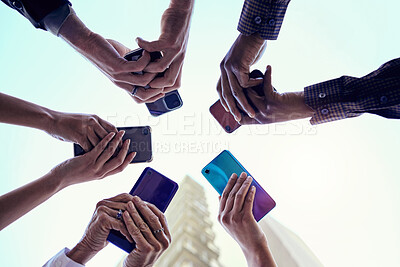 Buy stock photo Business people, hands and circle with phone, connectivity and social media in the city. Below, sky and group with hands holding mobile in urban town with internet, web and career app with diversity