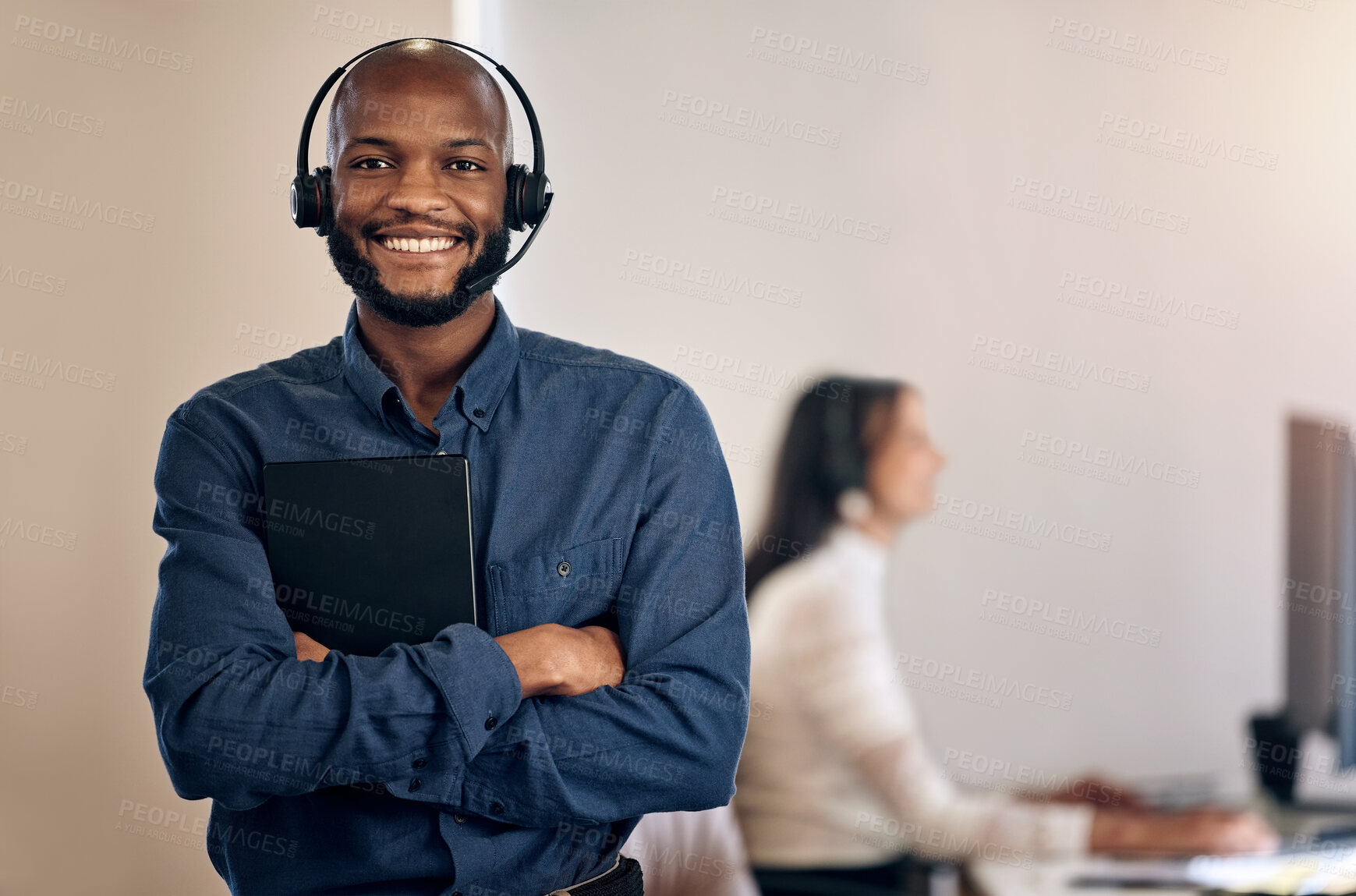 Buy stock photo Portrait of a young call centre agent using a digital tablet while working in an office with his colleague in the background