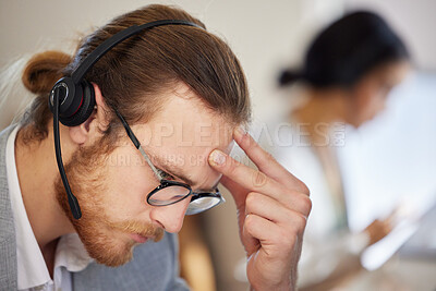 Buy stock photo Shot of a handsome customer service agent sitting in his office and feeling stressed