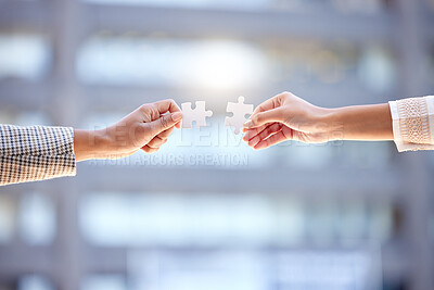 Buy stock photo Shot of two unrecognizable businesspeople holding two puzzle pieces against a city background