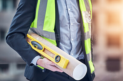 Buy stock photo Cropped shot of an unrecognizable male construction worker standing with blue prints and level on a building site