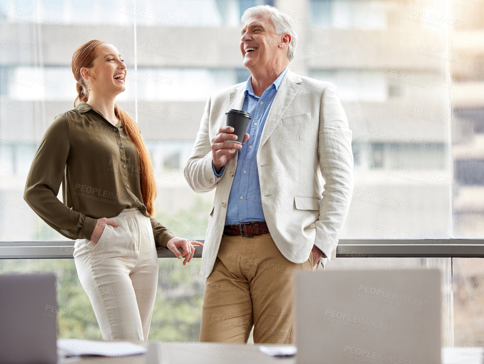 Buy stock photo Shot of two businesspeople standing together and laughing in the office