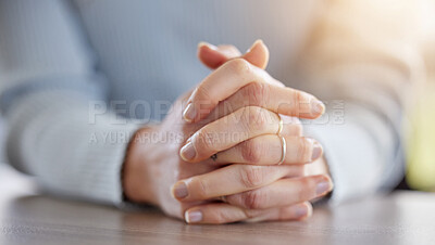 Buy stock photo Cropped shot of an unrecognisable businesswoman sitting alone in her office with her hands clasped