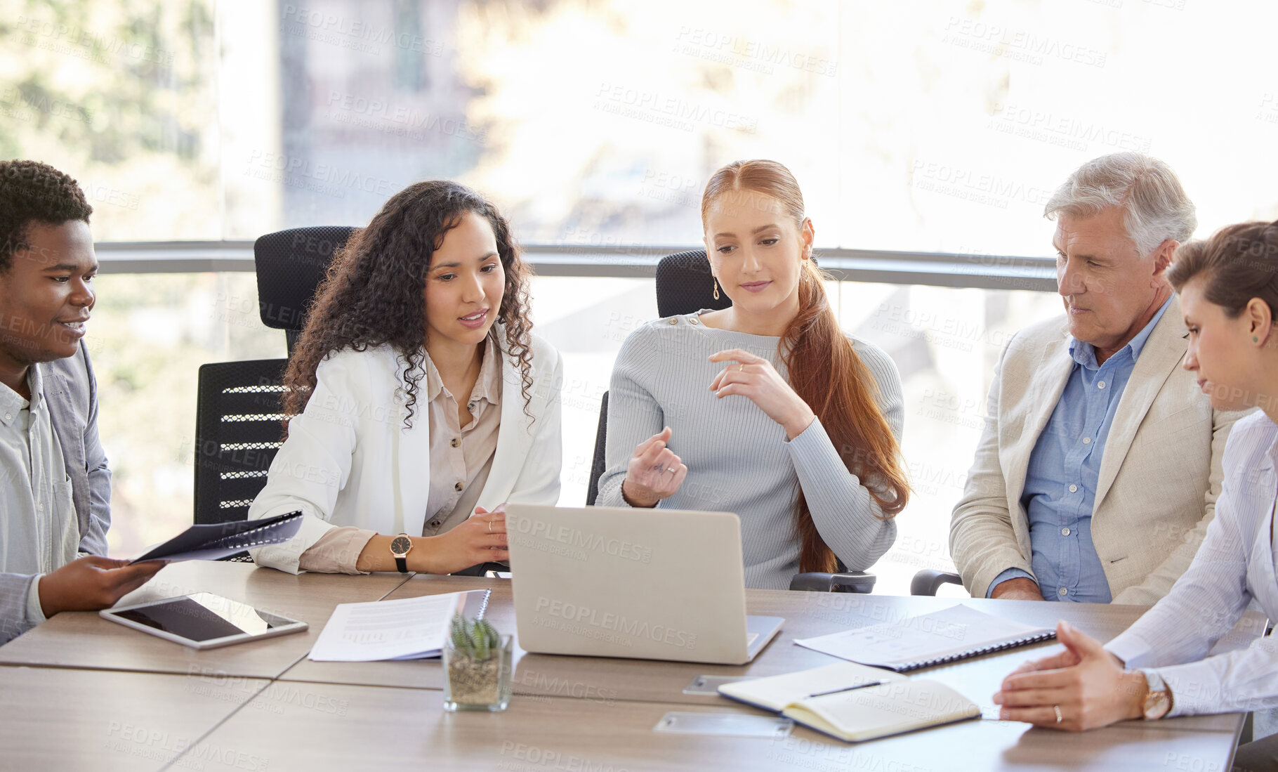 Buy stock photo Shot of a diverse group of businesspeople sitting in the office together and using a laptop during a meeting