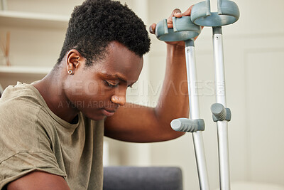 Buy stock photo Shot of a young man using crutches at home
