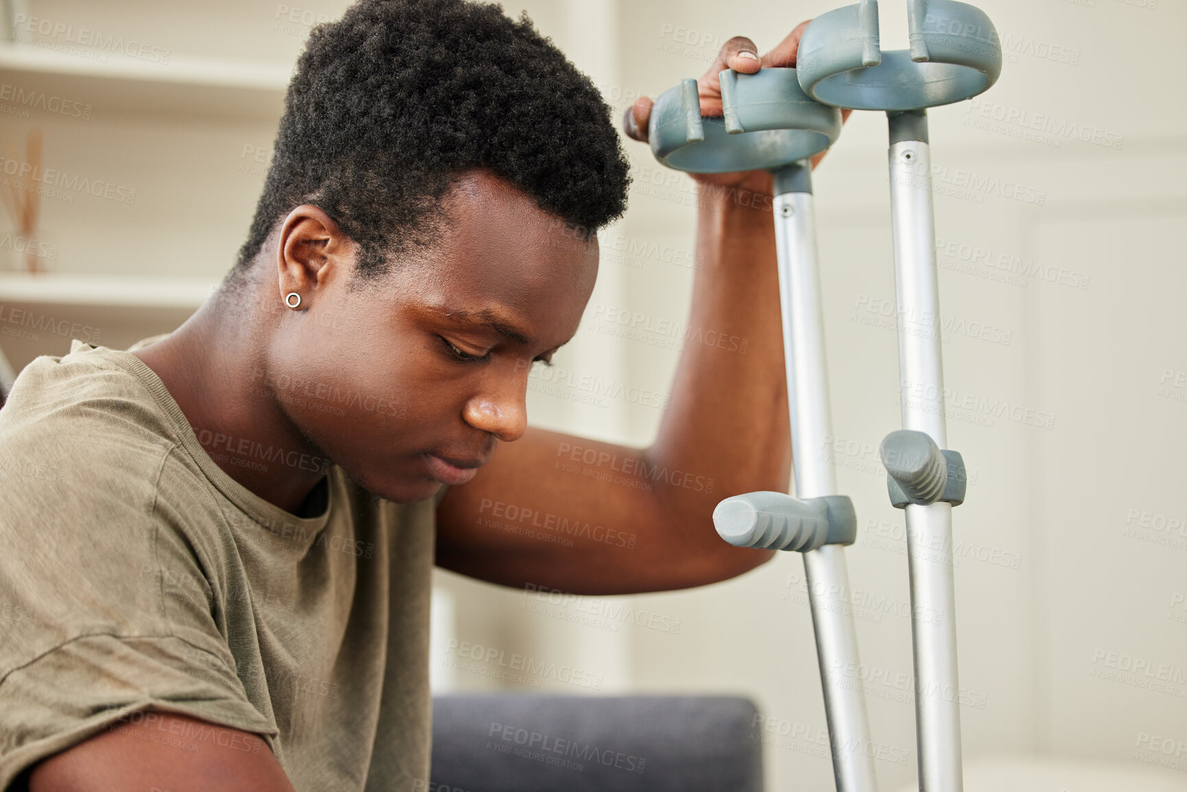 Buy stock photo Man, injury and depression on sofa with crutches for healing, recovery and mobility in home. African person, stress and unhappy with walking support on couch for mental health, accident and grumpy