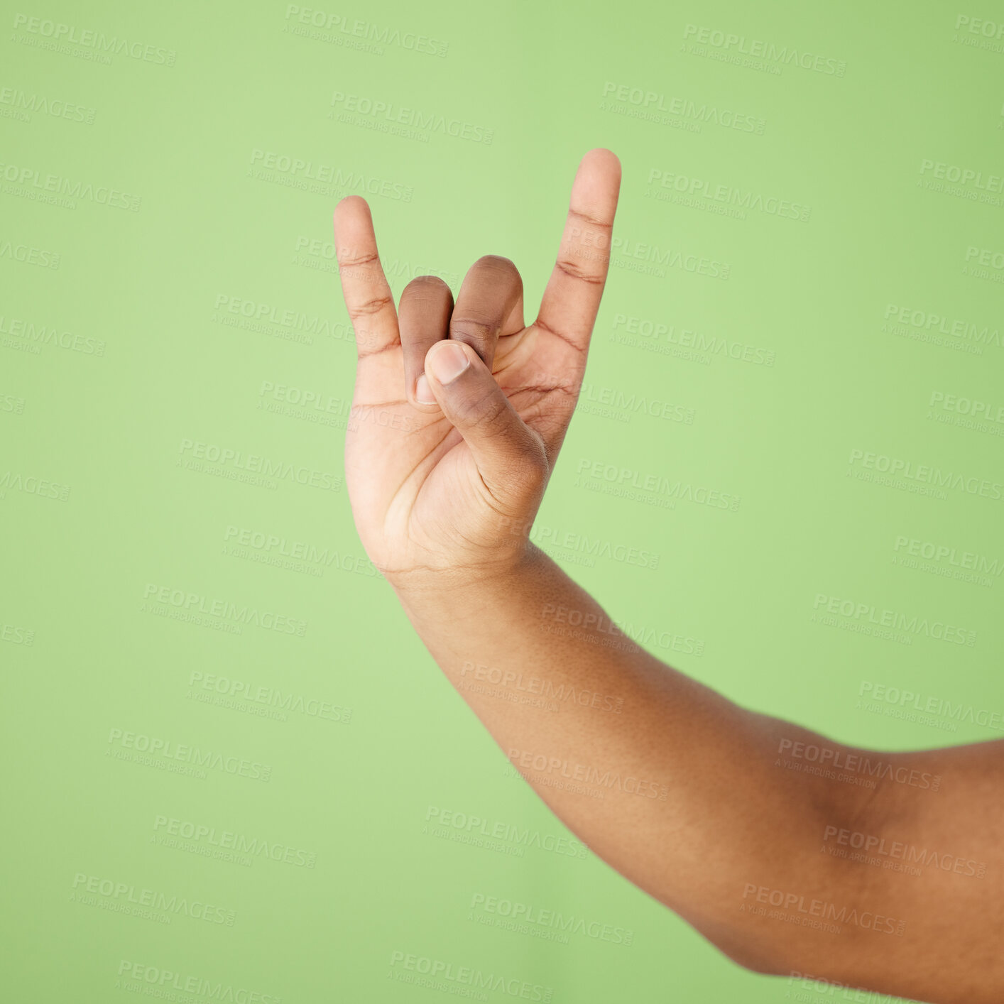 Buy stock photo Hands, person and rock and roll with hand gesture in studio for festival communication, punk sign and metal music. Devil horns, emoji and show power for culture opinion, funky and green background