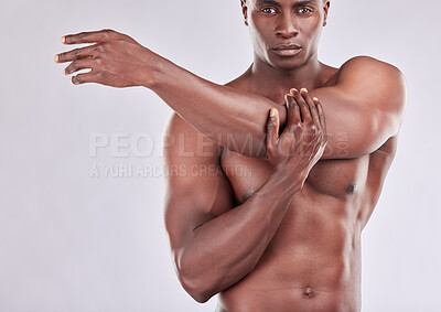 Buy stock photo Studio portrait of a muscular young man stretching his arms against a grey background