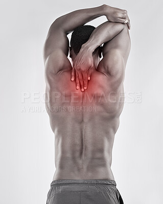 Buy stock photo Black and white shot of a muscular young man experiencing back pain against a grey background