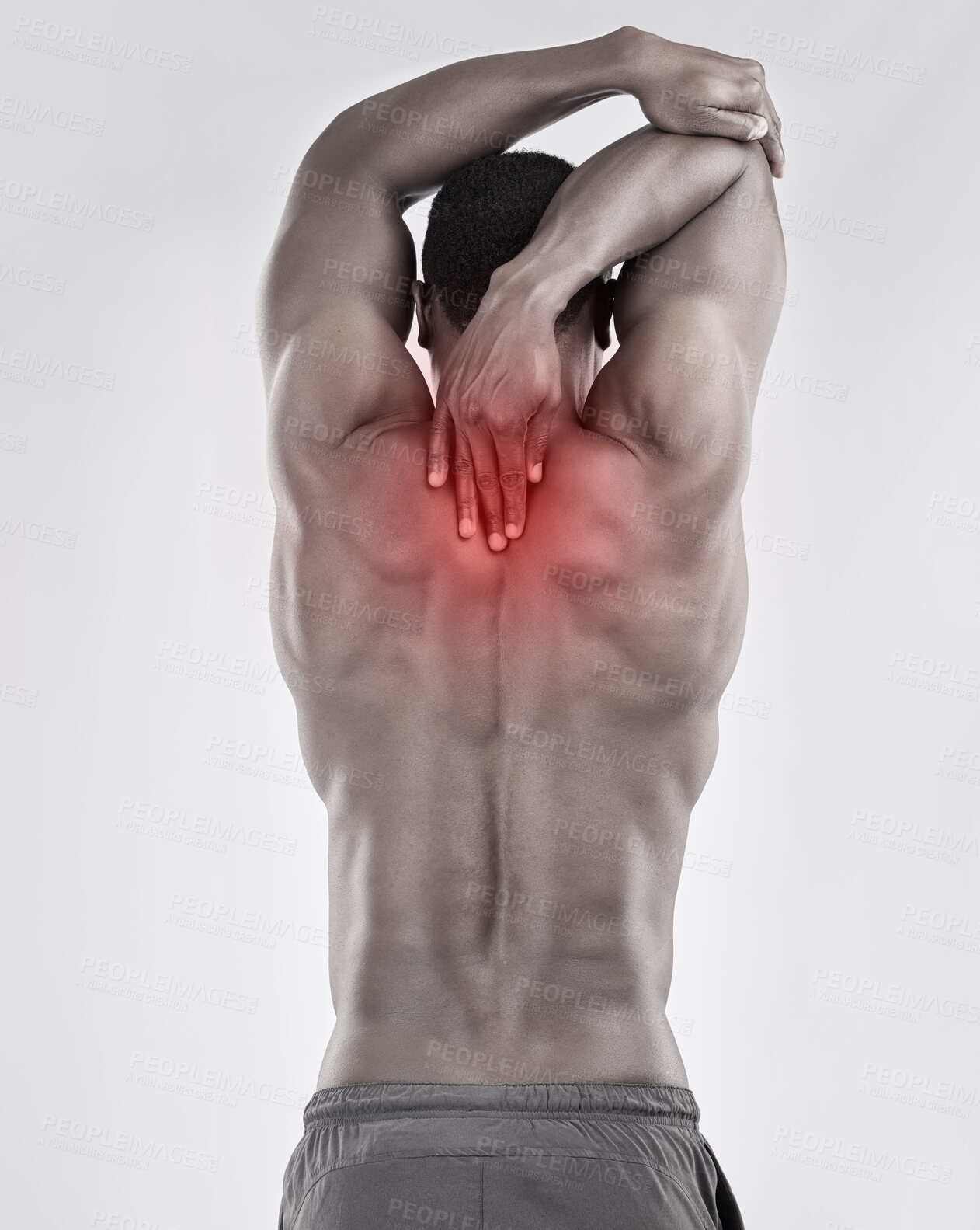 Buy stock photo Black and white shot of a muscular young man experiencing back pain against a grey background