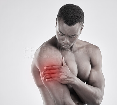 Buy stock photo Black and white shot of a muscular young man experiencing arm pain against a grey background