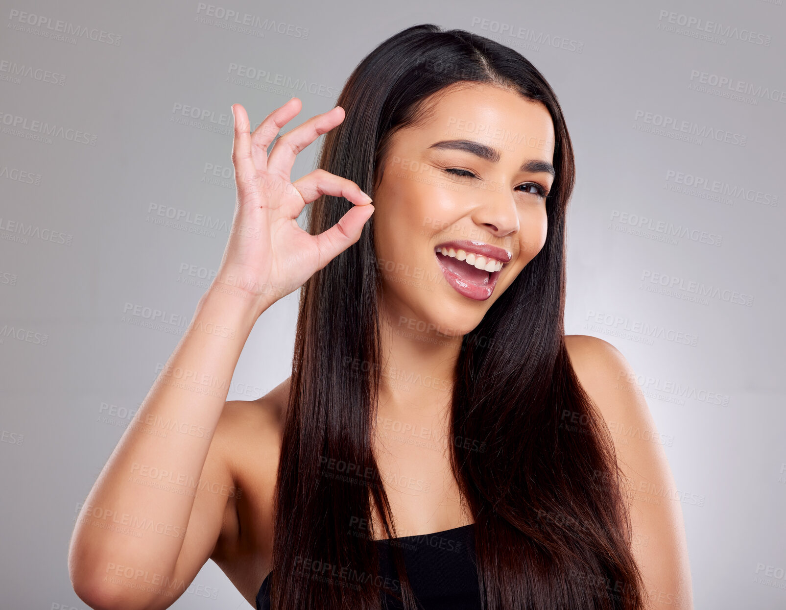 Buy stock photo Portrait, woman and okay for hair in studio with satisfaction, keratin treatment and growth of product health. Smile, female person and wink or hand sign, collagen shine and beauty on grey background