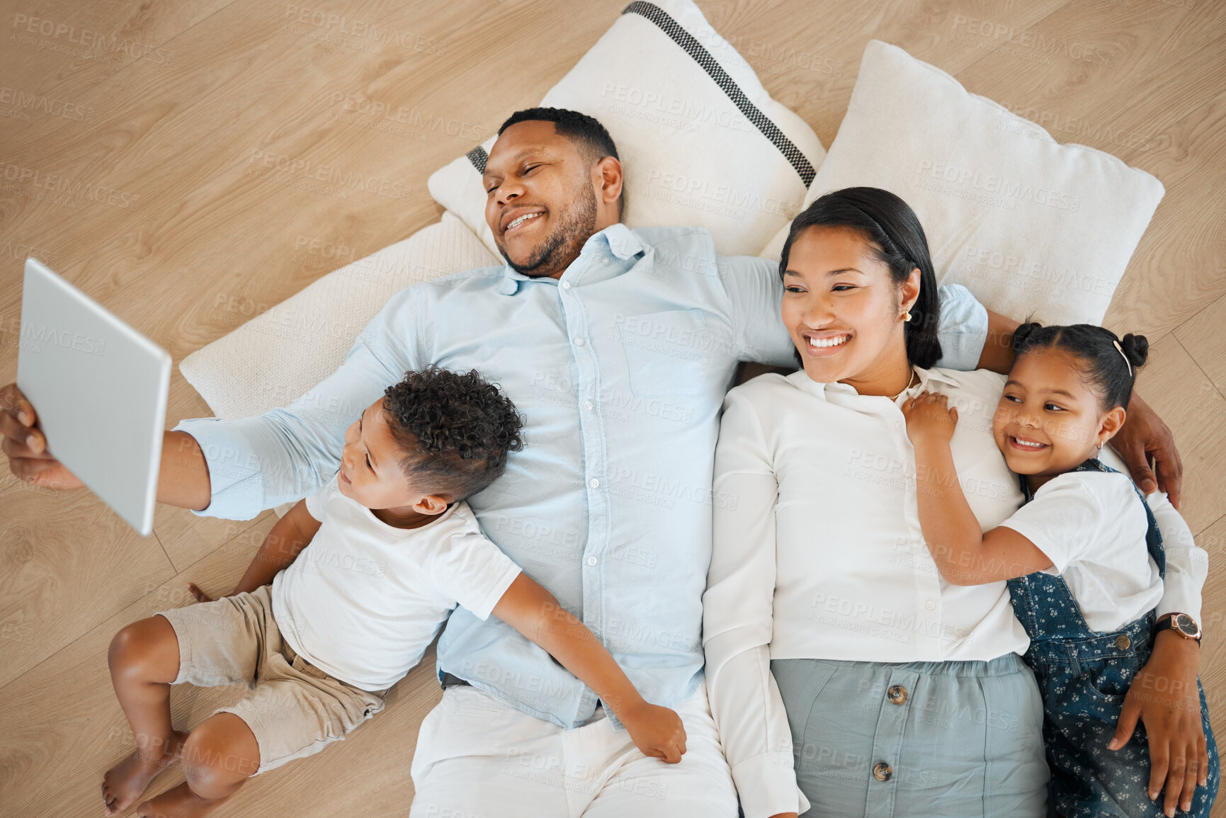 Buy stock photo Shot of a family laying on the floor and using a tablet at home
