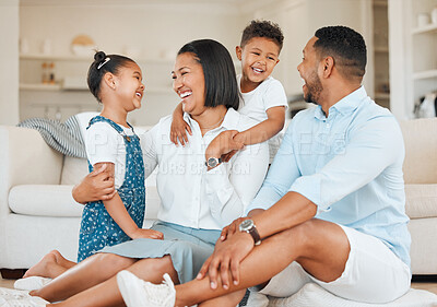 Buy stock photo Shot of a young family happily bonding together on the floor at home