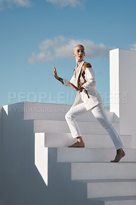 Buy stock photo Shot of a young model wearing stylish white clothes while walking up stairs against a sky background