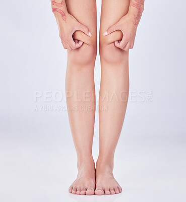 Buy stock photo Cropped shot of an unrecognizable woman holding her injured knee against a grey background