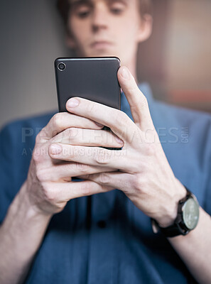 Buy stock photo Shot of a young businessman using his smartphone to send a text message