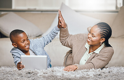 Buy stock photo Shot of a young mother and son giving each other a high five while using a digital tablet at home