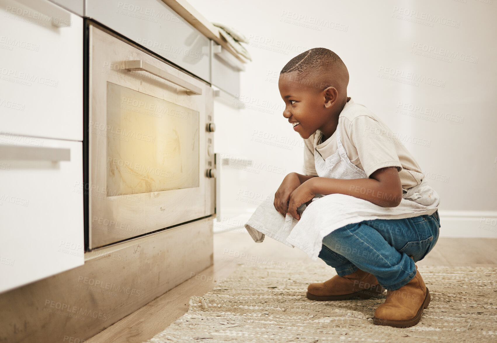 Buy stock photo Shot of a little boy watching his baked goods cook in the oven at home