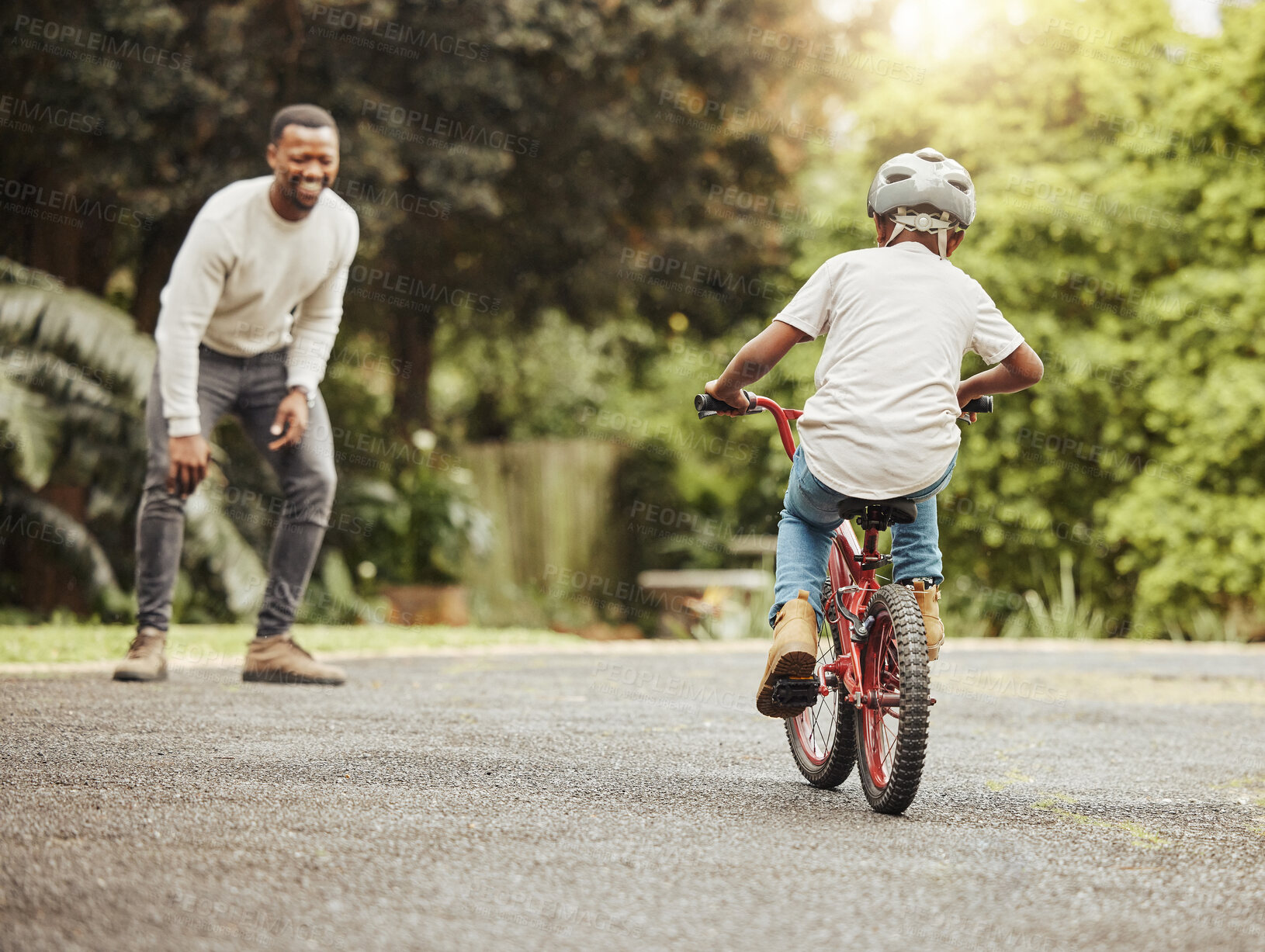 Buy stock photo Boy on bicycle, father cheers and learn cycling with help, helmet for safety and family in park. Support, motivation and trust, black man and young kid outdoor, teaching and learning bike riding