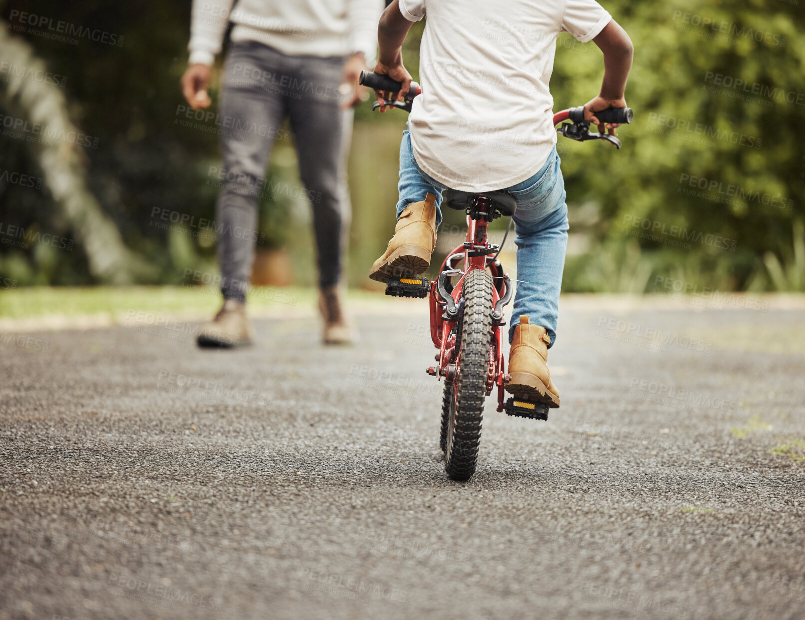 Buy stock photo Cropped shot of a boy learning to ride a bicycle with his father outdoors