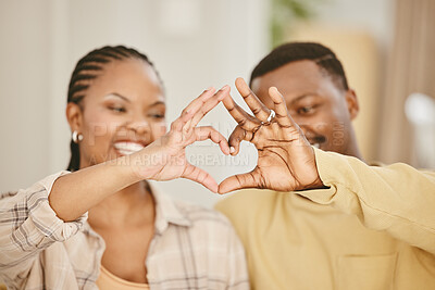 Buy stock photo Shot of a young couple forming a heart shape while sitting together at home
