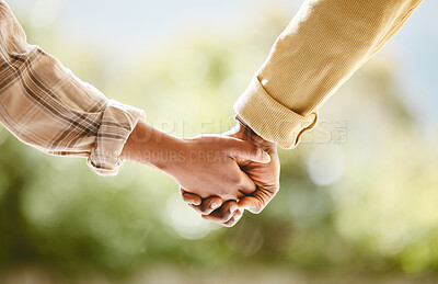 Buy stock photo Cropped shot of an unrecognizable couple holding hands while walking outside