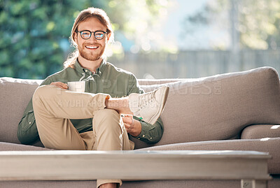 Buy stock photo Portrait of a young man enjoying a relaxing coffee break on the sofa at home
