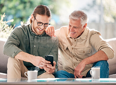 Buy stock photo Shot of a young man using a smartphone with his father on the sofa at home