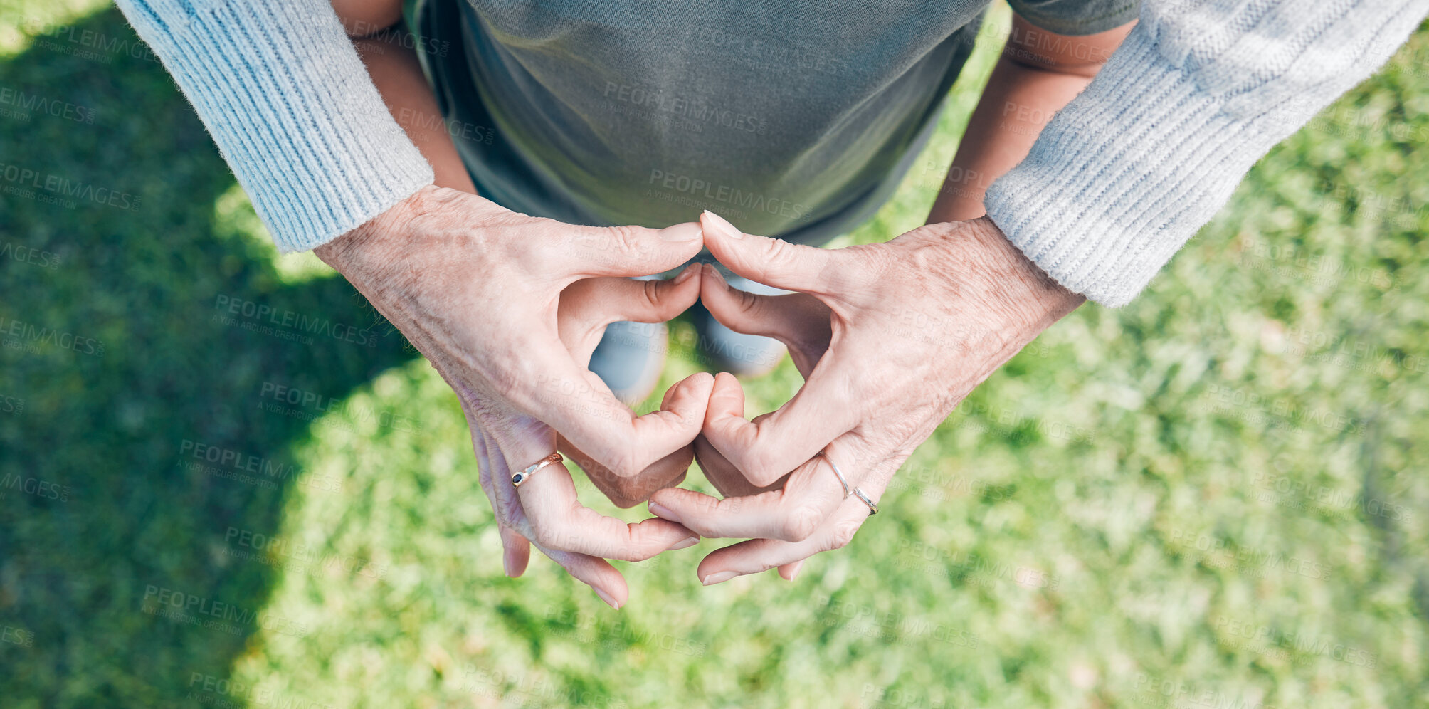 Buy stock photo Shot of an unrecognizable little boy and his grandmother holding their hands together in a heart shape outside