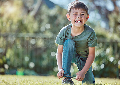 Buy stock photo Shot of an adorable little boy tying his shoelaces outside