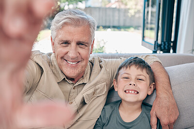 Buy stock photo Shot of an adorable little boy taking selfies with his grandfather at home