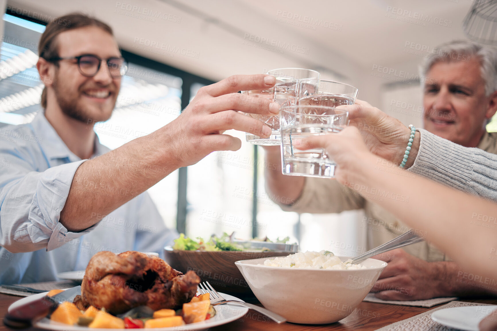Buy stock photo Shot of a family toasting with drinks while having a meal together at home