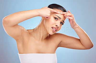 Buy stock photo Skincare, pimple and hands of woman in studio for cosmetics, natural or blemish treatment on blue background. Spa, body and model with stress for popping zit, acne breakout or wellness routine