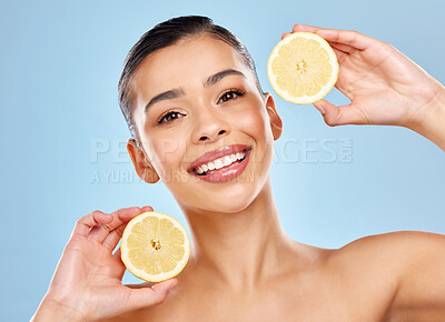 Buy stock photo Studio portrait of an attractive young woman posing with lemon against a blue background