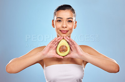 Buy stock photo Studio portrait of an attractive young woman posing with an avocado against a blue background