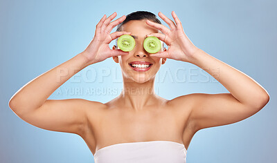 Buy stock photo Studio shot of an attractive young woman posing with kiwi against a blue background