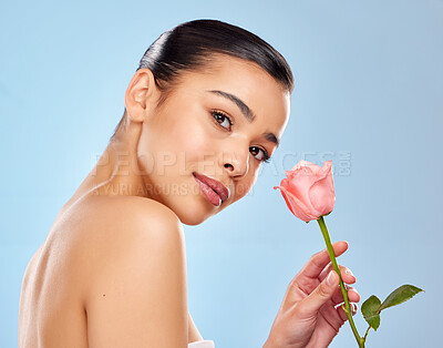 Buy stock photo Woman, skincare portrait and rose with beauty for eco friendly wellness and skin glow for healthy shine in studio. Model girl, flower and dermatology for sustainable cosmetics by blue background