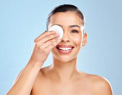Buy stock photo Studio portrait of an attractive young woman using a cotton pad on her face against a blue background