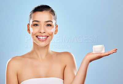 Buy stock photo Studio portrait of an attractive young woman holding a beauty product against a blue background