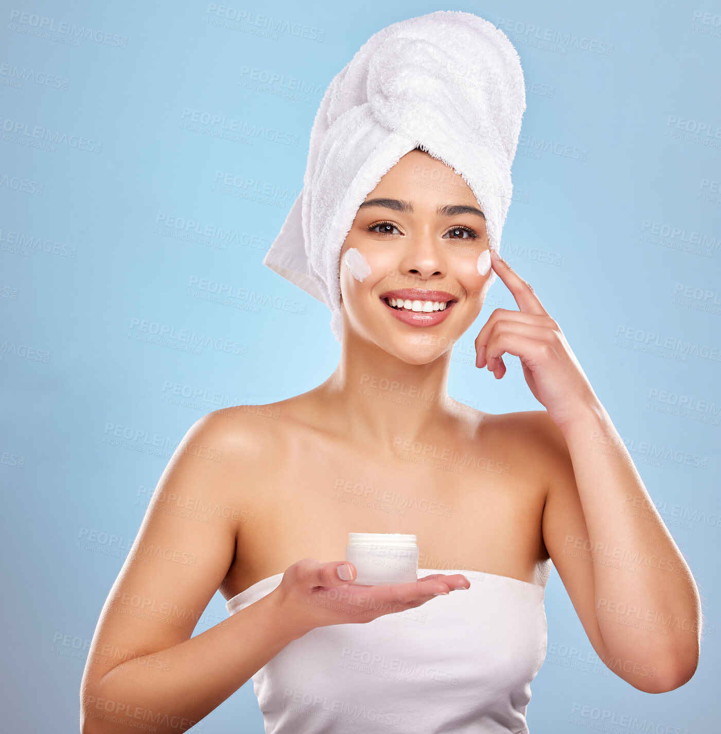 Buy stock photo Cream product, hands and woman portrait in studio with skincare for natural treatment, cosmetics or dermatology spa on blue background. Beauty, towel and model for shine, moisturizer or wellness