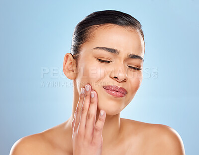 Buy stock photo Studio shot of an attractive young woman experiencing toothache against a blue background