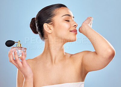Buy stock photo Studio shot of an attractive young woman applying perfume against a blue background