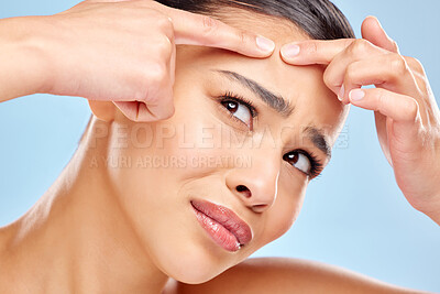 Buy stock photo Woman, pimple and squeeze in studio for beauty, skincare and remove blackhead on blue background. Female person, scratch and clean pores or acne, facial treatment and pop zit or spot on oily skin